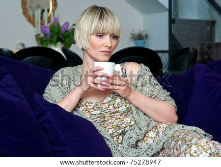 woman drinking coffee while sitting on the sofa at home living room