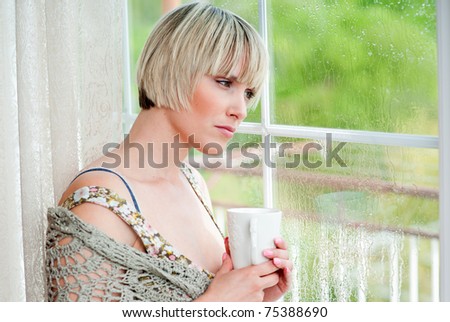 woman with morning coffee looking through window