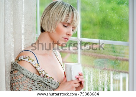 woman with closed eyes next to rainy window