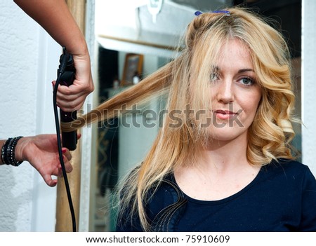 stylist curling woman hair and making new hairstyle in salon