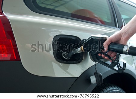woman hand holding fuel nozzle and refuel car in gas station