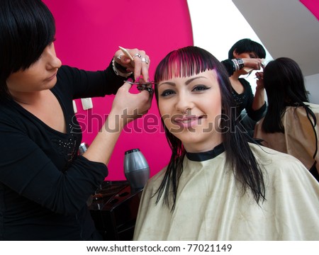 stylist making interesting haircut to teenage girl in salon