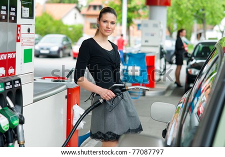woman holding fuel nozzle and refuel car in gas station