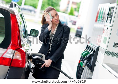 woman with money in her hand refuel car in gas station