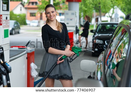 woman holding green nozzle at gas station