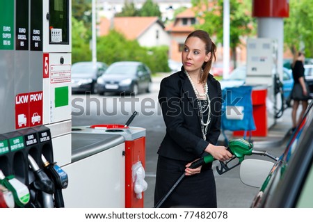 attractive elegant woman in black dress refuel car on gas station