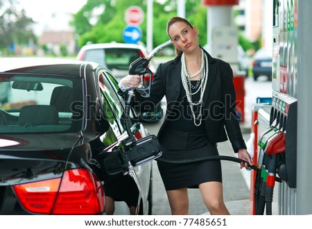 woman holding gas nozzle as gun pointed to her head