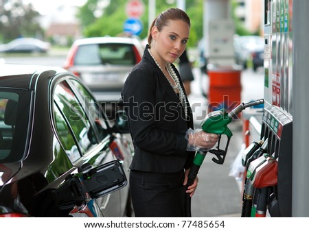 woman holding gas nozzle in gas station