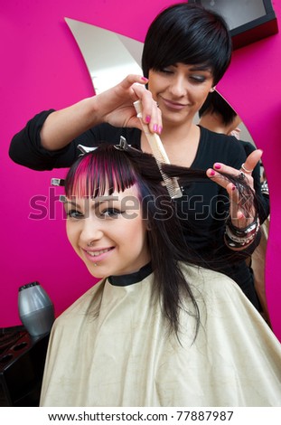 stylist making hair style to interesting teen girl