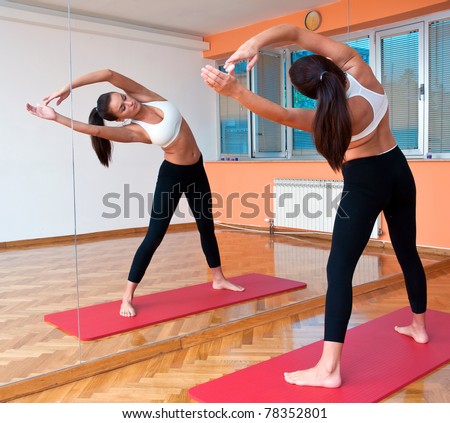 fit woman making stretching exercise in front of fitness studio mirror