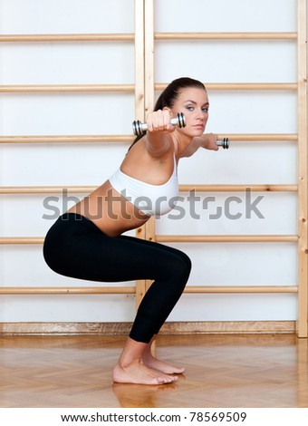 fit woman in fitness pose with weights in gym