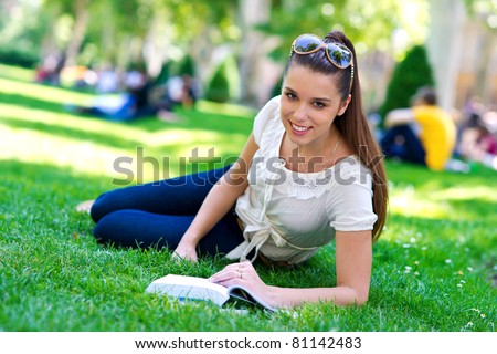 teen girl reading book in city park outside