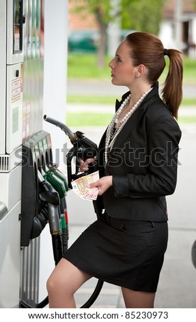 woman with money at gas station holding nozzle