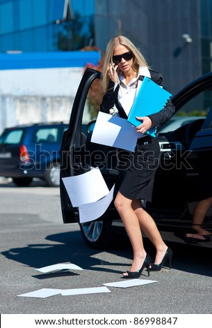 attractive business woman dropping papers near to her car in parking lot