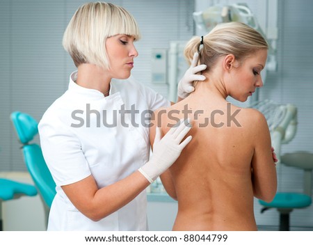 dermatologist doctor inspecting woman patients skin on her back
