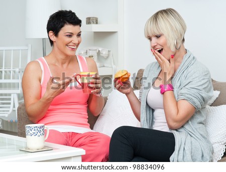 two happy woman friends chatting and smiling over coffee and cakes