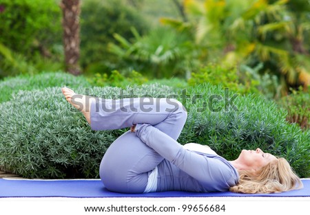 mature woman doing yoga position outside in the garden