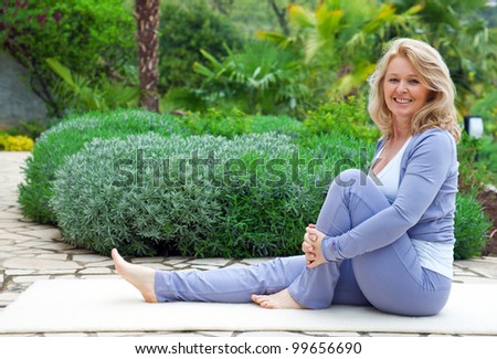 mature woman in relaxation yoga position outside in the garden