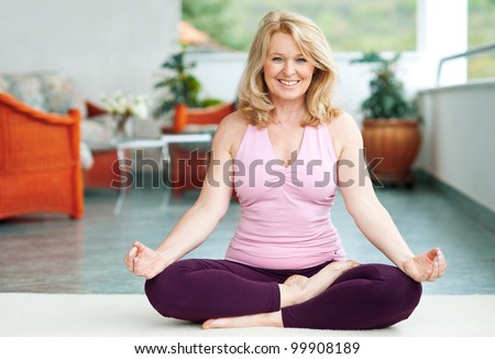mature woman doing lotus yoga position on her home balcony