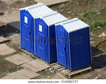 Three portable toilet cabins at the construction site surrounded by waste
