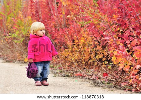 toddler girl walking along bright bushes