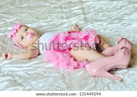 fashion 3 months old baby girl laying on the bed with high heels shoes