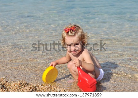 toddler girl playing toys in sea water