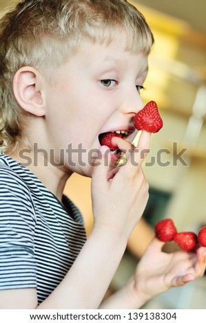 little funny boy is enjoying strawberry