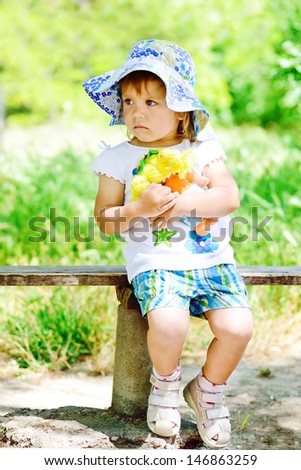 toddler girl with doll on the bench