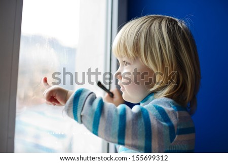 Sweet Toddler Girl Looking Through The Window