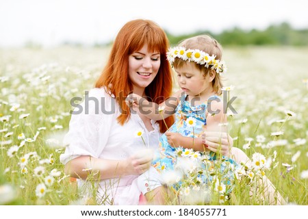 fun of little girl and redhead young woman in daisy field