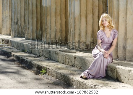 beautiful young model sitting near old columns