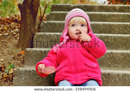 baby girl picking her nose outdoors