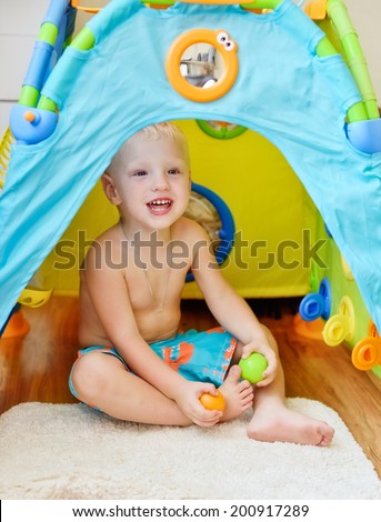 little boy plating at home with toy house