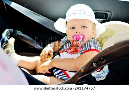 cute baby girl is sitting in car seat