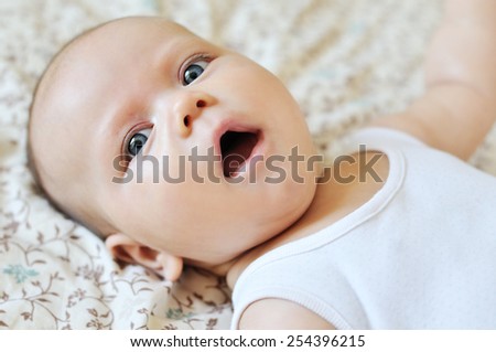 sweet baby with open mouth laying on the bed