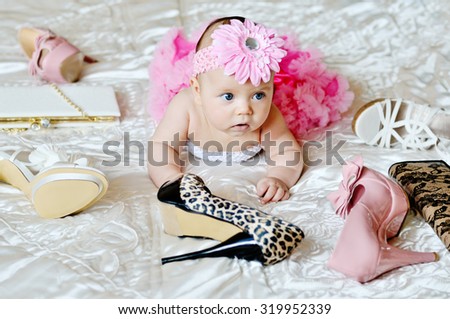 fashion baby girl laying on the bed with high heels shoes and bags
