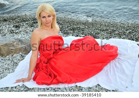 lady in red is sitting on the beach, alone