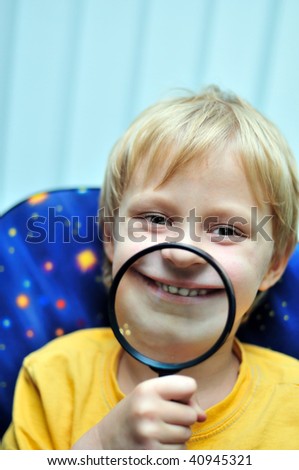 boy using	 magnifying glass to make a big grin
