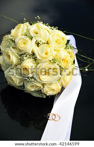 yellow  roses and wedding bands on the dark surface
