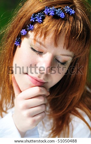 redheaded girl in the spring forest with flowers in her hair