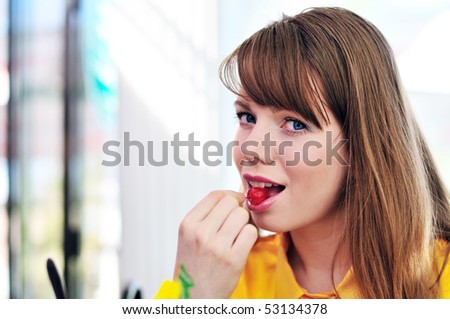 Young beautiful woman eating cherry in cafe