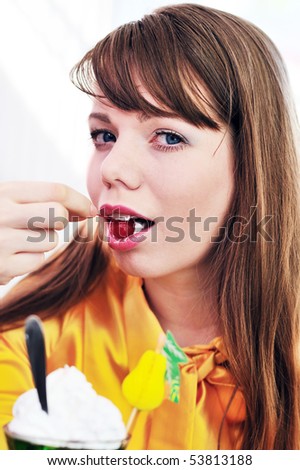 Young beautiful woman eating cherry and dessert in cafe