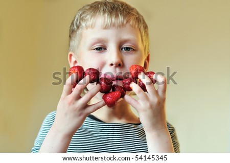 boy eating strawberry put on his fingers and smacking lips