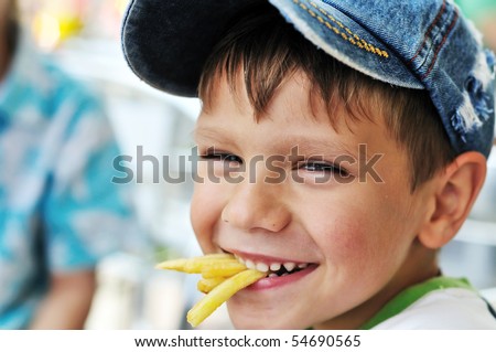 little boy eating french fries in cafe