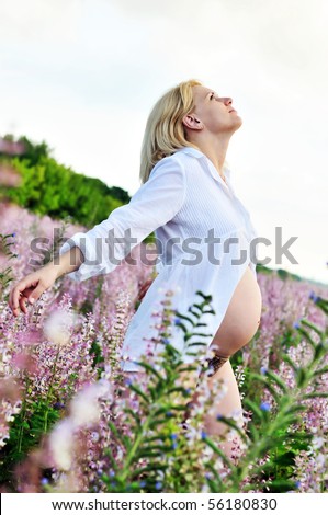 pregnant woman at one with nature pulling towards sun