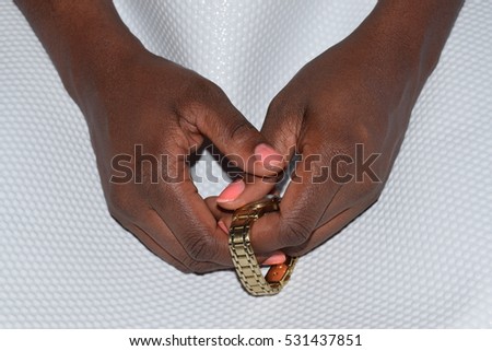 Black female hands holding a gold watch