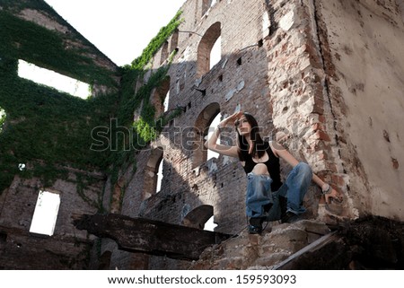 Woman in jeans in a deserted building looking to see if there is somebody coming.