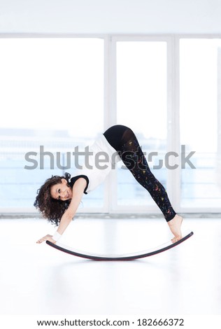 Pretty woman doing exercise with a new curved board concept.