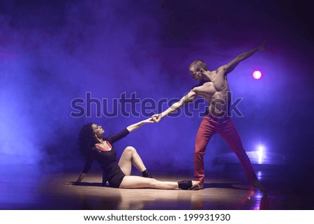 A man and a woman performing a contemporary dance pose on a stage.